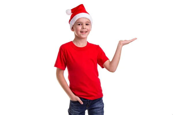 Schattige lachende jongen, Kerstman hoed op zijn hoofd, met de linkerhand horizontaal klaar voor het geschenk. Concept: Kerstmis of Happy New Year vakantie — Stockfoto
