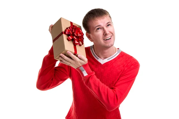 Handsome man in the red sweater, isolated white background. Wondering what is in the gift box — Stock Photo, Image