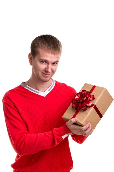 Szép ember a piros pulóver bemutató egy ajándék doboz elszigetelt fehér háttér — Stock Fotó