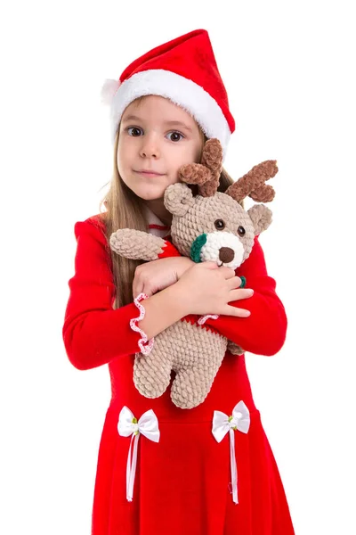 Ευτυχισμένος όμορφο κορίτσι Χριστούγεννα αγκαλιάζει το μαλακό παιχνίδι ελάφια, φορώντας ένα καπέλο santa απομονωμένη πάνω σε λευκό φόντο — Φωτογραφία Αρχείου