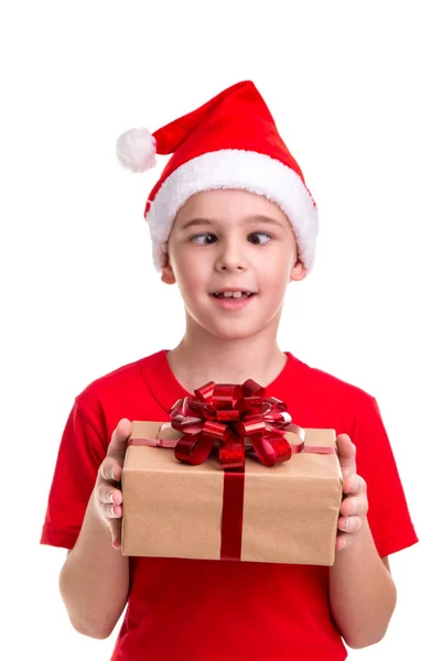 有趣的男孩 斜视着眼睛 圣诞老人的帽子戴在他的头上 手里拿着礼品盒 圣诞节或新年快乐假期 — 图库照片