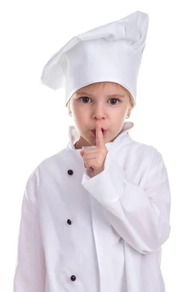 Chytré rozkošný dívka uniformě kuchař bílou izolovaných na bílém pozadí, drží blízko úst ukazováčkem. Ticho znamení. Obraz Portrét — Stock fotografie