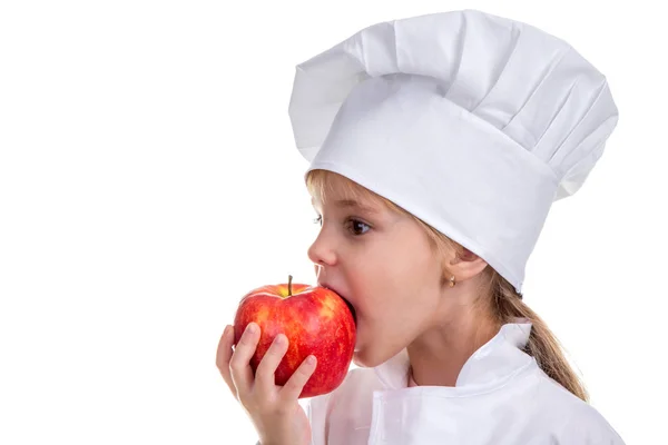 Kleines Mädchen mit Kochmütze, das in den roten Apfel beißt. Konzept gesunder Ernährung und gesunder Lebensweise. Profilbild — Stockfoto