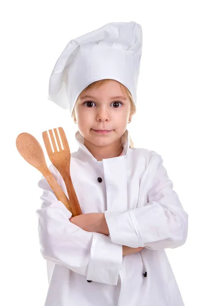 Smirking κορίτσι στολή σεφ λευκό απομονώνονται σε λευκό φόντο. Κρατώντας το ξύλινο κουτάλι και πιρούνι σε χέρια διπλωμένα. Πορτρέτο εικόνα — Φωτογραφία Αρχείου