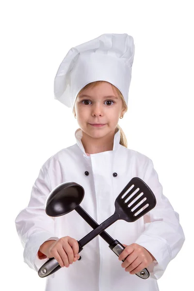 Sorrindo menina chef uniforme branco isolado no fundo branco. Segurando concha preta e escápula cruzada. Imagem do retrato — Fotografia de Stock