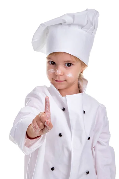Lány szakács fehér egységes elszigetelt fehér background. Nézi a kamerát. Lisztbe arc és ujját fel. Portré kép — Stock Fotó