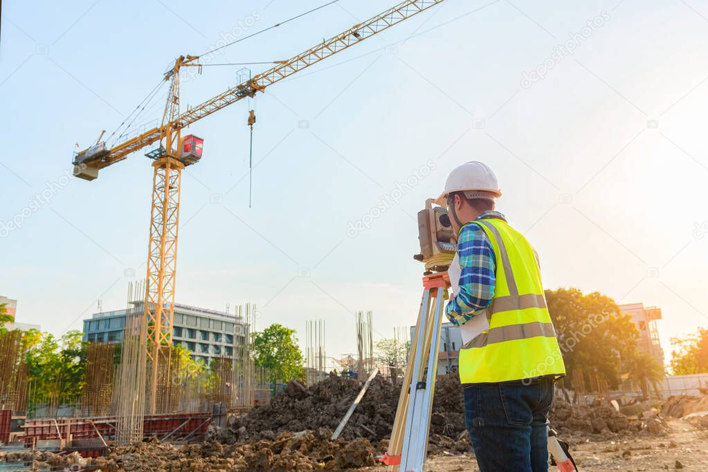 Surveying engineers are working together using theodolite on the construction site.
