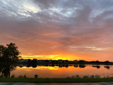 Güzel pembe, turuncu ve mavi gün batımı bir banliyö gölünde yansıyor..