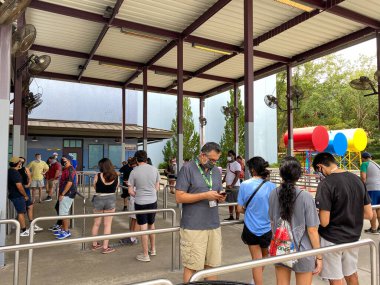 Orlando, FL / USA - 6 / 13 / 20: Coronavirus 'un yüz maskeleri ve sosyal mesafeler takması sonrasında Haziran 2020' deki yeniden açılış sırasında Universal Stüdyoları 'nda Örümcek Adam kuyruğundaki insanlar.