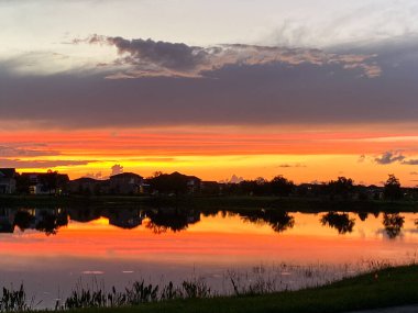 Güzel pembe, turuncu ve mavi gün batımı bir banliyö gölünde yansıyor..