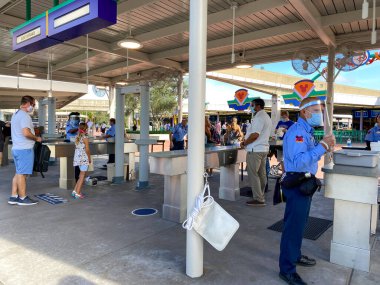 Orlando, FL / USA-7 / 25 / 20: Orlando, FL 'deki Walt Disney World Resorts' ta güvenlik kontrolü sırasında yüz maskesi takan ve sosyal mesafeli kişiler.
