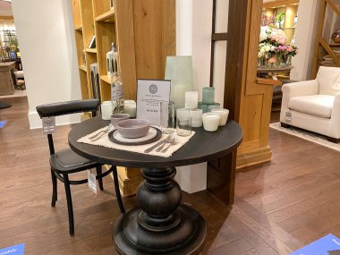 Orlando, FL / USA- 7 / 4 / 20: Orlando, Florida 'daki kapalı bir alışveriş merkezindeki Pottery Barn' da ahşap bir yemek masası ve sandalye.