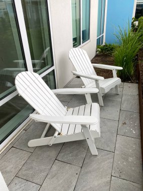 Verandada oturan iki Adirondack sandalyesi. Barışçıl, düşünceli, gevşemiş ve rahat bir yaşam tarzı..