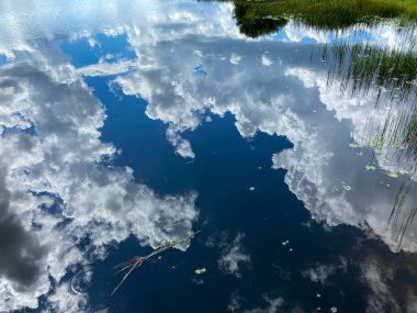Gökyüzündeki bulutlar güzel bir yaz gününde sakin ve huzurlu bir göle yansıyor..