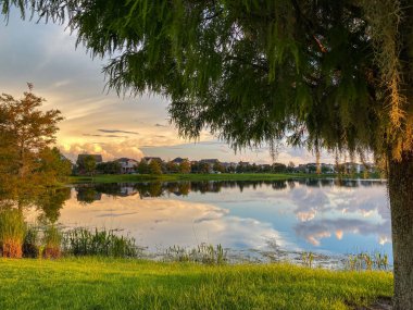 Güzel pembe, turuncu ve mavi gün batımı bir banliyö gölünde yansıyor..