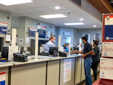 Orlando, FL / USA- 6 / 24 / 20: İnsanlar, Orlando, Florida 'da insanların yüz maskesi taktığı ve sosyal mesafeli davrandıkları bir ABD Posta Ofisi' ne paket postalıyorlar,