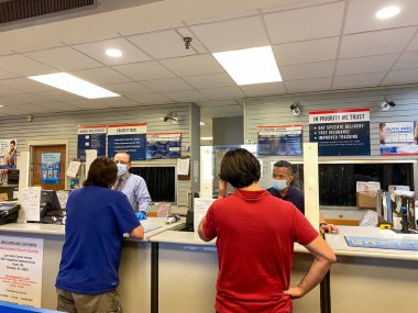 Orlando, FL / USA- 6 / 24 / 20: İnsanlar, Orlando, Florida 'da insanların yüz maskesi taktığı ve sosyal mesafeli davrandıkları bir ABD Posta Ofisi' ne paket postalıyorlar,