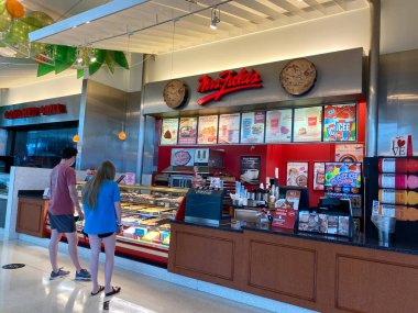 Orlando, FL / USA - 7 / 4 / 20: İnsanlar Orlando, Florida 'daki kapalı bir alışveriş merkezindeki Bayan Fields Cookie perakende mağazasından kurabiye alıyor.