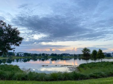 Güzel pembe, turuncu ve mavi gün batımı bir banliyö gölünde yansıyor..