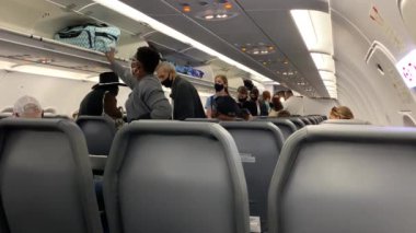 Orlando, FL / USA - 10 / 2 / 20: İnsanlar bagajlarını bir uçaktaki üst depolama kutusuna koyuyorlar