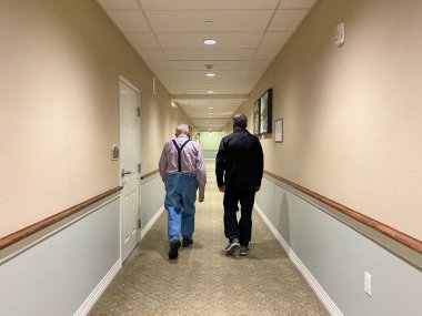 Springfield, IL ABD - 5 Ekim 2020: Yaşlı bir baba ve oğlu bir huzurevinin koridorunda yürüyor,