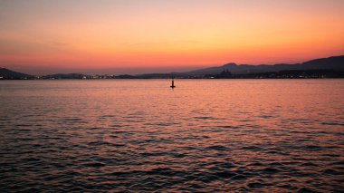 Arka planda deniz ve şehir üzerinde gün batımı