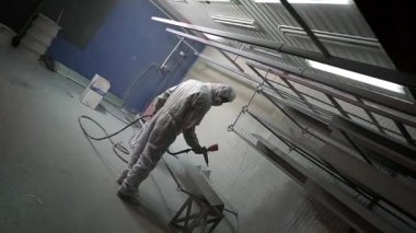 Toz kaplama. Sprey tabancalı adam metal nesnelere toz uyguluyor..