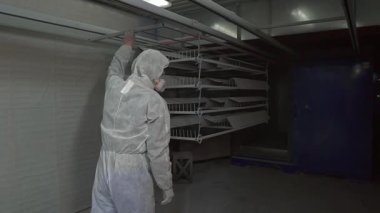 Man in protective suit respirator moves metal products in polymerization furnace