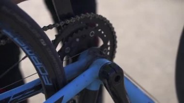 Bisikletçi pedalları eliyle takıyor. Bisikleti kontrol eden ve tamir eden bir sporcu