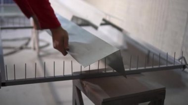 Kırmızı elbiseli bir adam barut kaplama odasına metal bir nesne yerleştirdi.