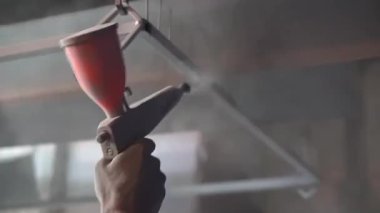 Toz kaplama. Sprey tabancalı adam eli metal nesneye pudra uygular.