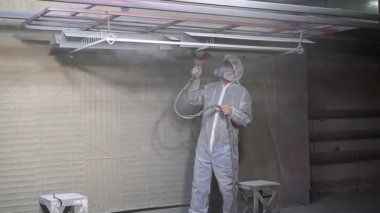 Toz kaplama. Sprey tabancalı adam metal nesnelere toz uyguluyor..