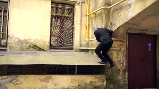 Man in zwart klimt op het dak aan de voorkant — Stockvideo