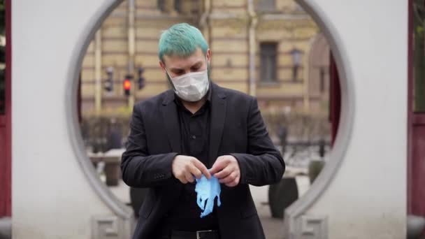 Gemaskerde man in een zwart pak trekt zijn handschoenen aan — Stockvideo