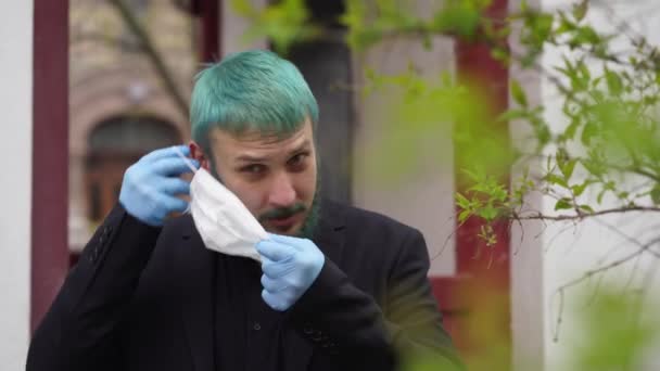 Man in black with dyed hair puts on a mask — Stock Video