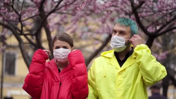 Man en vrouw verwijderen beschermende maskers in de straat — Stockvideo
