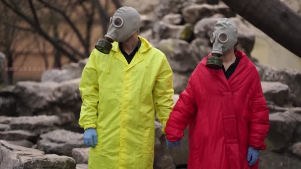 A man and a woman stand in the street in gas masks holding hands — Stock Video