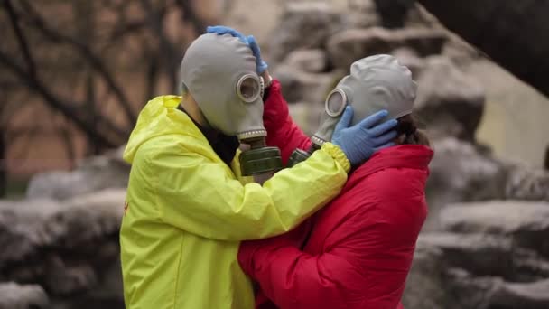 Mann und Mädchen in Gasmasken und Handschuhen umarmen sich — Stockvideo