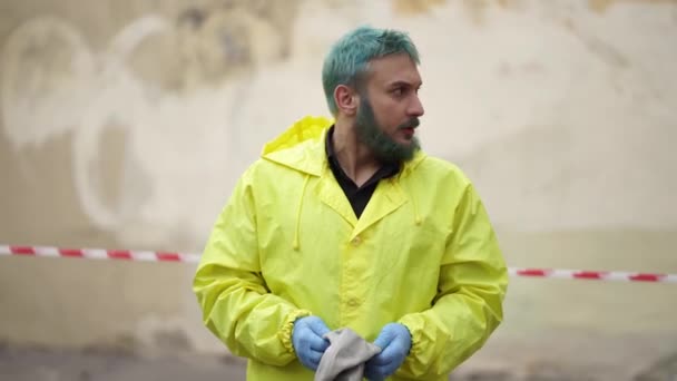 Mężczyzna w żółtej kurtce i rękawiczkach zakłada maskę gazową na ulicy — Wideo stockowe
