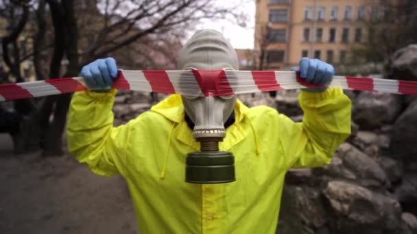 Muž ve žluté bundě v plynové masce se dotkne ochranné pásky v rukavicích — Stock video