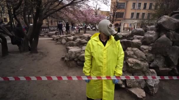 Een man met een gasmasker staat voor een beschermende tape op straat — Stockvideo