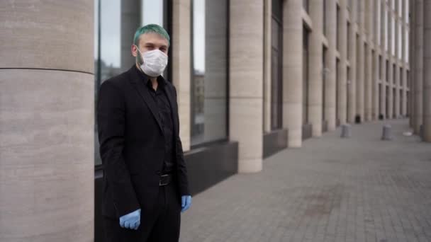 A man in a mask and a black suit stands near the building — Stock Video