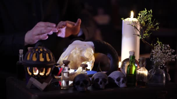 Une séance de magie à la lumière des chandelles dans une pièce aux crânes humains — Video