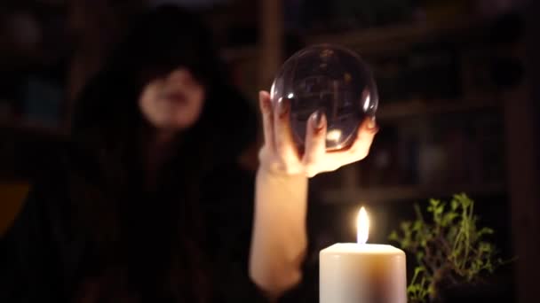 Adivinación en una bola de cristal junto a velas encendidas — Vídeo de stock