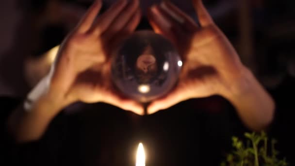 Waarzeggerij op een kristallen bol naast brandende kaarsen — Stockvideo
