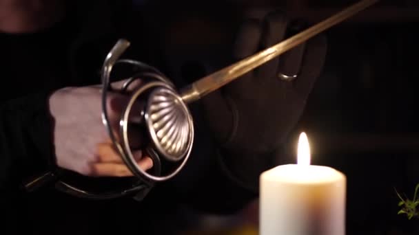 Sword glows over the flame of a wax candle — Stock Video