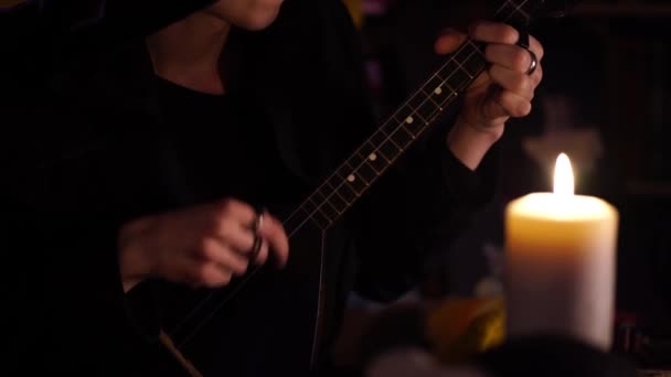 Μαύρος μάγος παίζει σε μαύρο balalaika από το φως των κεριών — Αρχείο Βίντεο