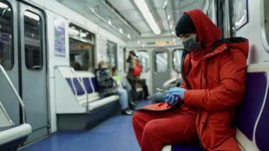 Maskeli ve eldivenli beyaz bir adam metro vagonuna biniyor.