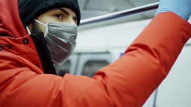 Maskeli ve eldivenli beyaz bir adam metro vagonuna biniyor.