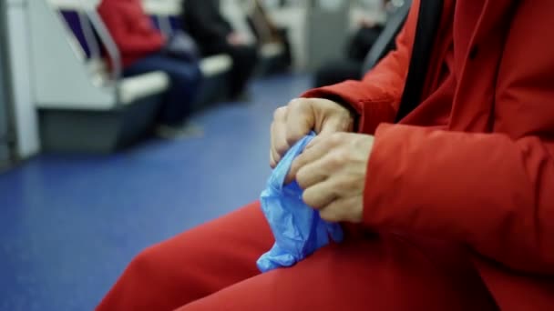 Мужчина надевает резиновые перчатки в метро — стоковое видео